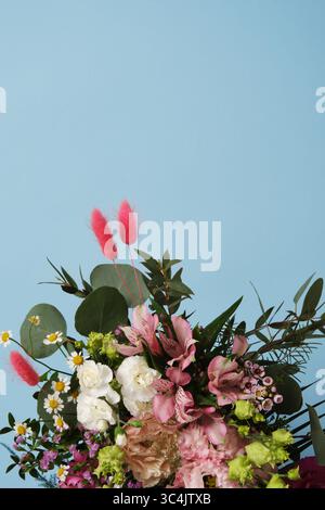 Bouquet floral lumineux sur un fond bleu. Roses, œillets, eustoma, alstromeria. Copyspace Banque D'Images