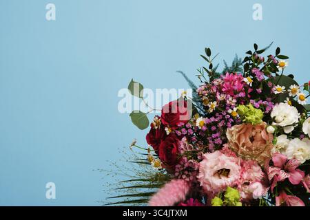 Fond floral avec un bouquet de roses, œillets, eustoma, alstromeria sur fond bleu. Copyspace Banque D'Images