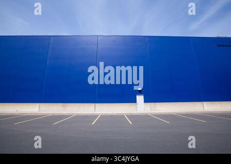 Parking vide près du centre commercial avec grand mur bleu de magasin et ciel bleu. Image de haute qualité à télécharger Banque D'Images