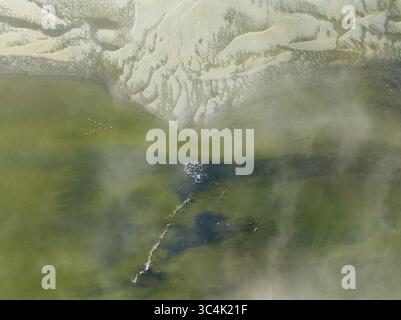 Vue aérienne du bord de la lagune où le sable blanc rencontre les eaux vertes, un rassemblement d'oiseaux près de l'eau, Walvis Bay, Walvis Bay Lagoon, Namibie. Banque D'Images
