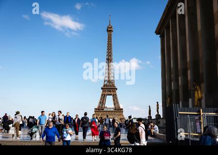 Une scène parisienne vibrante se déroule, mettant en scène la Tour Eiffel sous un ciel bleu clair. Les touristes se promènent sur une place, créant un quartier animé mais paisible Banque D'Images