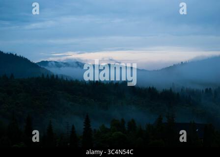 Crêtes montagneuses silhouettées enveloppées de brume bleue Banque D'Images