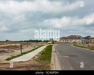 Perspective de nouvelle rue et trottoir partiel par terrasseur près de plusieurs maisons unifamiliales en construction dans un développement de banlieue, Floride Banque D'Images