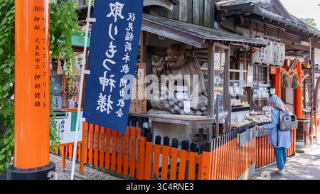 Une statue en bois et une boîte de prière dans un kiosque souvenir et offre dans le sanctuaire Fushimi Inari à Kyoto, au Japon. 06.29.2025. Kyoto, Japon. Banque D'Images