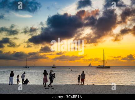 Les gens sur la plage comme le soleil se couche. Banque D'Images
