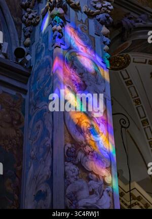 Une image de l'intérieur de l'église Saint Nicolas, à Valence, frappée par la lumière du soleil reflétée par des vitraux colorés. Banque D'Images