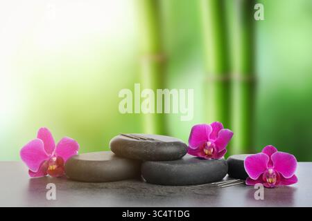 Aiguilles d'acupuncture, pierres de spa et fleurs sur table à l'extérieur Banque D'Images