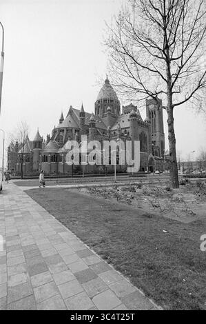 Extérieur de la basilique de Bavo Haarlem on the Leidsevaart, Exterior, Haarlem, Leidsevaart, pays-Bas, 28-04-1973 Whizgle News, Dutch Desk, pays-Bas, 1950-2000 Un grand bâtiment orné de détails architecturaux complexes, entouré d'un espace paysager avec des allées et des arbres. La structure présente un mélange de tours et de toits uniques, créant une présence visuelle saisissante. Une figure solitaire marche le long du sentier, soulignant l'échelle de l'édifice. Banque D'Images