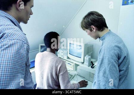 Internet par câble à Haarlem, Haarlem, pays-Bas, 30-09-1997 Whizgle News, Dutch Desk, pays-Bas, 1950-2000 trois individus sont rassemblés autour d'un ordinateur, intensément concentrés sur l'écran. Une personne est assise, tapant activement, tandis que les autres se tiennent à proximité, observant avec curiosité. La salle dispose d'une configuration minimaliste, avec divers équipements informatiques et une atmosphère lumineuse et aérée. Banque D'Images