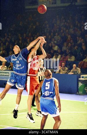 Haarlem Basketball week : Hapoel Eilat - Bowling Green, Haarlem, pays-Bas, 00-12-1995 Whizgle News, Dutch Desk, pays-Bas, 1950-2000 deux joueurs de basket-ball sautent pour un ballon lâche tandis qu'un troisième joueur observe depuis le terrain. L'action capture l'intensité du jeu, mettant en évidence l'athlétisme et la compétition. Les fans peuvent être vus en arrière-plan, ajoutant à l'atmosphère vibrante du match. Banque D'Images