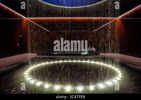 Musée national d'histoire et de culture afro-américaines Cour contemplative Washington DC | WASHINGTON D.C., États-Unis — L'eau coule à travers un oculus éclairé dans la Cour contemplative, un espace de rassemblement méditatif à l'intérieur du Musée national Smithsonian d'histoire et de culture afro-américaines. Baignée de verre caramel cuivre-bronze par Bendheim, la salle se trouve au niveau 0 du hall, reliant les galeries d'histoire du musée et ses galeries culturelles au-dessus. Des citations gravées de Nelson Mandela, Dr Martin Luther King Jr. et Sam Cooke tapissent ses murs, renforçant les thèmes o Banque D'Images