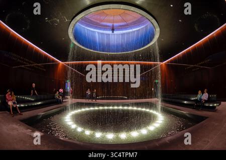 Musée national d'histoire et de culture afro-américaines Cour contemplative Washington DC | WASHINGTON D.C., États-Unis — les visiteurs se reposent sur des bancs dans la cour contemplative du musée national Smithsonian d'histoire et de culture afro-américaines alors que l'eau tombe d'un oculus au-dessus d'un bassin réfléchissant éclairé. La cour, au niveau 0 du hall, relie les galeries d'histoire du musée et ses galeries de culture au-dessus, ses murs de verre cuivre-bronze gravés de citations de Nelson Mandela et Frances Ellen Watkins Harper. Le musée a ouvert ses portes en 2016 sous le nom de 19e Smithsonian Banque D'Images