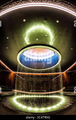 Musée national d'histoire et de culture afro-américaines Cour contemplative Washington DC | WASHINGTON D.C., États-Unis — des feuilles d'eau coulent d'un oculus circulaire dans la Cour contemplative, un espace intérieur méditatif au sein du Musée national d'histoire et de culture afro-américaines. Des panneaux de verre cuivre-bronze de Bendheim, développés pour les architectes Freelon Adjaye Bond/SmithGroup, entourent la salle et portent un passage gravé Martin Luther King Jr. Qui fait écho aux thèmes de liberté et de justice du bâtiment. Banque D'Images