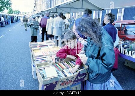 Marché du livre le long de la Spaarne, Haarlem, Spaarne, pays-Bas, 27-06-1998 Whizgle News, Dutch Desk, pays-Bas, 1950-2000 Un marché de rue animé présente des gens qui parcourent divers stands, avec un parent et un enfant engagés dans l'exploration d'une collection de livres. L'atmosphère est animée, remplie de clients et de vendeurs le long de l'avenue. Banque D'Images