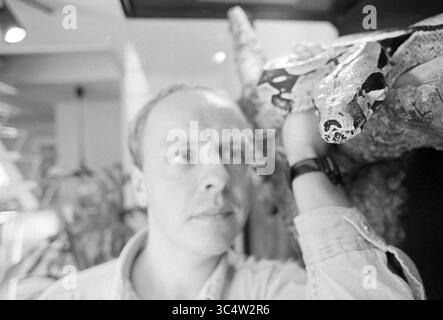 Jean Paul Janus - boa constrictor, 28-09-1993 Whizgle News, Dutch Desk, pays-Bas, 1950-2000 Un homme regarde attentivement alors qu'il tient un grand serpent sur son bras, montrant un moment d'interaction entre l'humain et le reptile. L'arrière-plan fait allusion à un environnement vibrant, rempli de vie végétale. Banque D'Images