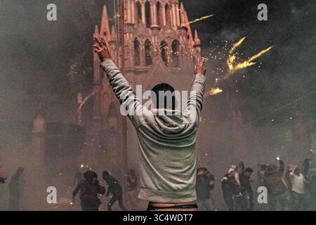 29 septembre 2018 - San Miguel de Allende, Guanajuato, Mexique - Un mexicain lève les bras à l'église de l'Archange San Miguel lors d'un barrage de fusées aériennes au festival Alborada le 29 septembre 2018 à San Miguel de Allende, Mexique. Le festival insolite célèbre le saint patron des villes avec une bataille de feu d'artifice de deux heures à 4h du matin représentant la lutte entre Saint Michel et Lucifer. (Crédit image : © Richard Ellis/ZUMA Wire) Banque D'Images