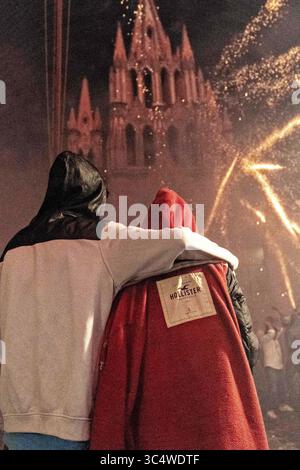 29 septembre 2018 - San Miguel de Allende, Guanajuato, Mexique - Un couple s'embrasse alors qu'ils regardent des fusées aériennes exploser autour d'eux devant l'église de l'Archange San Miguel pendant le festival d'Alborada le 29 septembre 2018 à San Miguel de Allende, Mexique. Le festival insolite célèbre le saint patron des villes avec une bataille de feu d'artifice de deux heures à 4h du matin représentant la lutte entre Saint Michel et Lucifer. (Crédit image : © Richard Ellis/ZUMA Wire) Banque D'Images