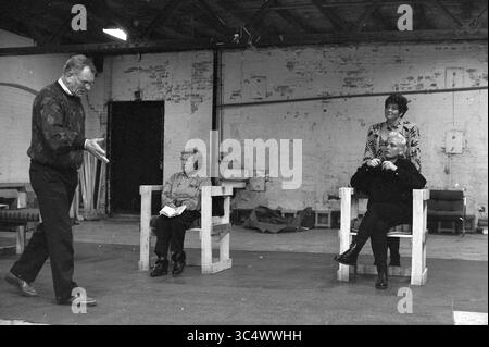 Théâtre 'Advendo', IJmuiden, IJmuiden, pays-Bas, 22-11-1992 Whizgle News, Dutch Desk, pays-Bas, 1950-2000 Un groupe de quatre personnes s'engage dans une conversation dynamique dans un espace industriel rustique. Une personne se tient debout, exprimant des idées animées, tandis que deux autres s'assoient attentivement dans de simples chaises en bois, et une quatrième se tient à proximité, observant l'interaction. Le cadre fait allusion à une répétition ou à une séance de brainstorming créative, mettant en évidence un moment de collaboration. Banque D'Images