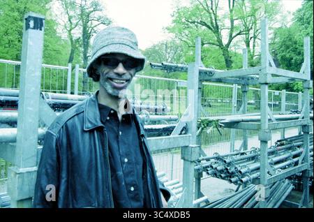 Poupée libération Gil Scott-Heron Haarlem, Haarlem, pays-Bas, 04-05-1998 Whizgle News, Dutch Desk, pays-Bas, 1950-2000 Un homme portant des lunettes de soleil et un chapeau seau se tient à côté d'une structure métallique remplie de tuyaux, entouré d'un environnement verdoyant et luxuriant. Il sourit avec confiance, dégageant une ambiance détendue dans un contexte industriel. Banque D'Images