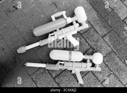 Pistolets à eau, Super Soakers, 20-07-1993 Whizgle News, Dutch Desk, pays-Bas, 1950-2000 deux pistolets à eau jouets sont disposés sur une surface texturée. Le pistolet supérieur dispose d'un design élégant avec un dessus arrondi et une poignée, tandis que le pistolet inférieur a une apparence plus robuste avec des détails supplémentaires et une buse plus grande. Les deux sont dans des couleurs vives, mettant en valeur des designs ludiques adaptés pour le plaisir en plein air. Banque D'Images