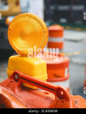 Un feu d'avertissement jaune vif se trouve au sommet d'une barricade orange, soulignant sa présence dans une zone de construction. Banque D'Images