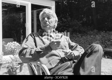 Notaire M. Roeda, Santpoort, Santpoort, 28-05-1997 Whizgle News, Dutch Desk, pays-Bas, 1950-2000 Un homme distingué se détend dans une chaise, tenant une pipe, tout en engageant une conversation. Il porte une chemise décontractée et apparaît profondément dans la pensée, entouré de verdure et d'un cadre tranquille. Banque D'Images