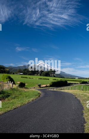 Tronçon de route courbe menant au mont Taranaki dans la campagne verdoyante près de Pitone, Île du Nord, Nouvelle-Zélande Banque D'Images