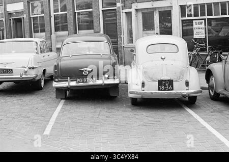 Erreurs de circulation Haarlemmers dans la section de circulation Echo 18 films., trafic, trafic sécurisé, Haarlem, Kinderhuisvest, pays-Bas, 00-09-1964 Whizgle News, Dutch Desk, pays-Bas, 1950-2000 Une rangée de voitures anciennes stationnées près les unes des autres dans une rue pavée, présentant des designs classiques et des plaques d'immatriculation du passé, avec une vitrine et des vélos visibles en arrière-plan. Banque D'Images