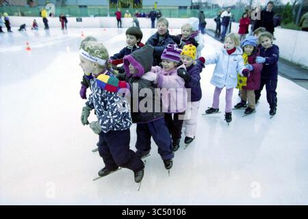 Parcours de patinage, Kras Sport, Haarlem, pays-Bas, 26-12-2002 Whizgle News, Dutch Desk, pays-Bas, 1950-2000 Un groupe d'enfants en vêtements d'hiver patinent joyeusement en ligne sur une patinoire, certains riant et souriant alors qu'ils se tiennent l'un sur l'autre pour l'équilibre. La scène capture l'excitation d'une journée amusante sur la glace. Banque D'Images