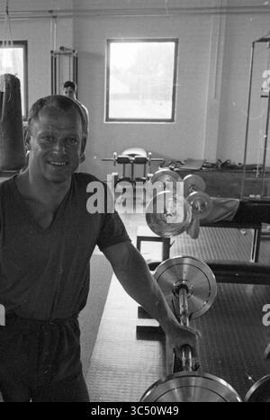 Centre de fitness Wim Witteman Zijlweg, sauna, gymnases, Haarlem, Zijlweg, 01-07-1981 Whizgle News, Dutch Desk, pays-Bas, 1950-2000 Un homme musclé sourit en toute confiance à côté d'un équipement d'haltérophilie dans une salle de sport bien équipée. En arrière-plan, un autre individu peut être vu s'engager dans l'espace d'entraînement. De grandes fenêtres permettent à la lumière naturelle de remplir la pièce. Banque D'Images