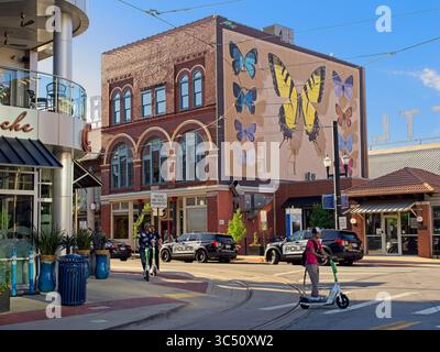 Scooters motorisés croisent l'intersection de River Market Ave sous la murale papillon sur le River Market dans le centre-ville de Little Rock Arkansas - mai 2025 Banque D'Images