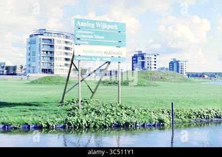 Sign construction Neighborhood Park (Client : municipalité de Velsen), Velsen, 00-10-1996 Whizgle News, Dutch Desk, pays-Bas, 1950-2000 Un panneau de construction est placé en évidence dans une zone herbeuse, indiquant l'aménagement d'un parc géré par la municipalité. En arrière-plan, les bâtiments résidentiels modernes s'élèvent contre un ciel dégagé. Banque D'Images