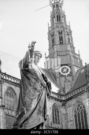 Rapport Loutje, Grote Markt, Report, Haarlem, Grote Markt, pays-Bas, 09-08-1972 Whizgle News, Dutch Desk, pays-Bas, 1950-2000 Une statue historique se dresse bien en vue devant une grande église, avec une grande tour de l'horloge derrière elle affichant l'heure. L'architecture complexe du bâtiment présente des toits pointus et des sculptures détaillées, créant une toile de fond saisissante pour la figure qui se déplace vers le haut. Banque D'Images