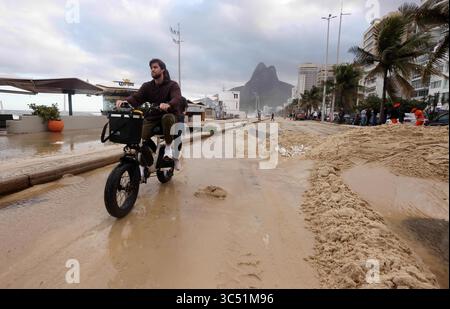 29 juillet 2025, Rio de Janeiro, Rio de Janeiro, Brésil : un homme conduit un vélo motorisé dans l'avenue Delfim Moreira, alors que des équipes de nettoyage municipales de Rio de Janeiro de Comlurb ont été dépêchées pour aider à nettoyer les suites d'une puissante tempête hivernale qui a envoyé des vagues de l'océan déferler sur la plage lors d'un rare événement d'onde de tempête, inondant la promenade Leblon et l'avenue Delfim Moreira. La vague violente a causé d'importants dommages à plusieurs kiosques en bord de mer et dispersé des débris sur la côte normalement animée. (Crédit image : © Bob Karp/ZUMA Press Wire) USAGE ÉDITORIAL SEULEMENT ! Non destiné à UN USAGE commercial ! Banque D'Images