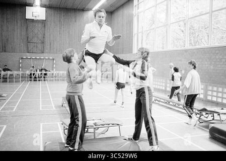 Gymnastique pour les patients cardiaques chez CIO, gymnastique, 11-05-1983 Whizgle News, Dutch Desk, pays-Bas, 1950-2000 un groupe d'athlètes engagés dans un entraînement de gymnastique, avec une personne effectuant un saut tandis que d'autres fournissent soutien et encouragement. L'environnement présente de l'équipement de gymnastique et des spectateurs en arrière-plan, soulignant un sentiment de camaraderie et l'accent mis sur la performance physique. Banque D'Images
