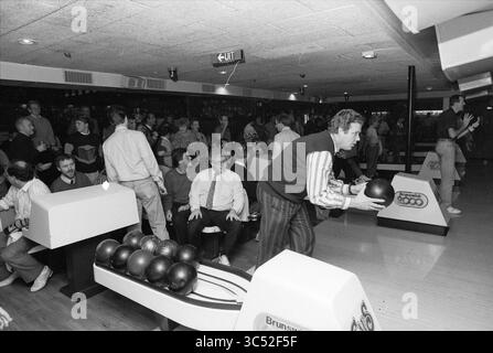 Compétitions de bowling contre des quilles sur une piste de bowling, 02-12-1990 Whizgle News, Dutch Desk, pays-Bas, 1950-2000 Une scène de piste de bowling animée mettant en scène un groupe de personnes rassemblées autour des pistes. Certains sont assis sur des bancs de bowling, tandis que d'autres se préparent à se relayer, mettant en valeur une atmosphère animée remplie de camaraderie et d'esprit de compétition. Les boules de bowling sont alignées, prêtes à l'action. Banque D'Images
