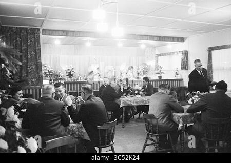 Pavillon intérieur Schonenberg, intérieur, 27-11-1963 Whizgle News, Dutch Desk, pays-Bas, 1950-2000 Un rassemblement d'individus élégamment habillés assis à des tables ornées de centres floraux, engagés dans la conversation et dégustant un repas dans une salle chaleureusement décorée avec un éclairage doux et des rideaux floraux. Banque D'Images