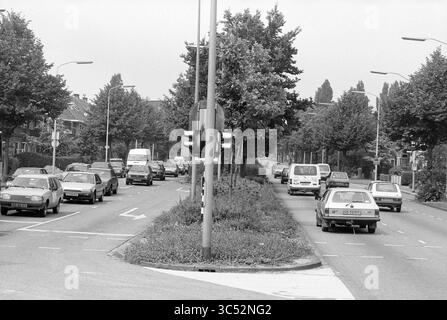 Trafic automobile sur Heemsteedsedreef, Heemstede, Heemsteedse Dreef, pays-Bas, 20-06-1990 Whizgle News, Dutch Desk, pays-Bas, 1950-2000 Une scène de rue animée présente plusieurs véhicules circulant le long d'une route bordée d'arbres, avec des feux de circulation dirigeant le mouvement. Le cadre comprend des bâtiments résidentiels en arrière-plan et un mélange de voitures, créant une atmosphère urbaine typique. Banque D'Images
