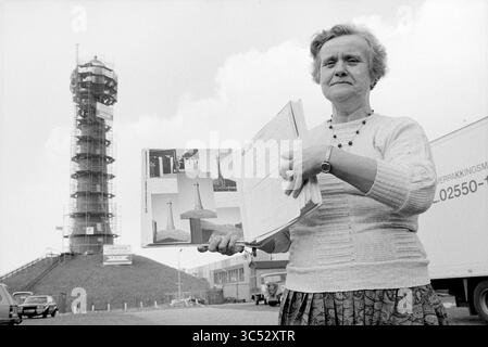MRS Poppe avec photos au phare d'IJmuiden, Lighthouse, IJmuiden, pays-Bas, 24-02-1987 Whizgle News, Dutch Desk, pays-Bas, 1950-2000 Une femme tient fièrement un album rempli d'images, devant une grande tour partiellement construite. Elle semble engagée et enthousiaste, montrant son lien avec le projet. Le cadre comprend des véhicules et des éléments de construction en arrière-plan, faisant allusion à un environnement de travail occupé. Banque D'Images