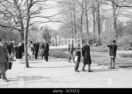 Le roi et la reine du Népal visitent Keukenhof, le domaine de la Fondation Keukenhof à lisse, Stationsweg, 27-04-1967 Whizgle News, Dutch Desk, pays-Bas, 1950-2000 Un groupe d'individus élégamment habillés se promène dans un jardin bien entretenu, entouré d'arbres en herbe et de tulipes en fleurs. Certaines personnes s'engagent dans la conversation tandis que d'autres marchent délibérément, créant un sentiment de mouvement et d'interaction sociale dans un cadre extérieur serein. Banque D'Images