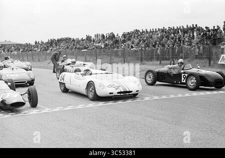 Courses automobiles, 21-06-1964 Whizgle News, Dutch Desk, pays-Bas, 1950-2000 Un groupe de voitures de course classiques aligné sur la grille de départ, avec des spectateurs enthousiastes regardant depuis les lignes de touche. La scène capture l'anticipation d'une course palpitante sur le point de commencer, mettant en vedette à la fois des véhicules élégants et des pilotes dévoués prêts à l'action. Banque D'Images