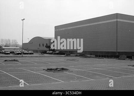 DIRECTEURS INFORMATIQUES extérieurs, Kennemer Sportcenter, IJsbaanlaan 4A, Haarlem. CIOS signifie Central Institute for Training Sports leaders., Haarlem, IJsbaanlaan, pays-Bas, 01-11-1993 Whizgle News, Dutch Desk, pays-Bas, 1950-2000 Un grand bâtiment moderne avec un extérieur élégant se dresse à côté d'une autre structure avec un design distinctif et incurvé. Un parking vide s'étend devant, avec quelques voitures stationnées éparpillées. La scène transmet un sentiment de calme et de désolation, mettant en évidence les caractéristiques architecturales des bâtiments contre un paysage aride. Banque D'Images