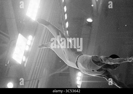 Championnats du monde femmes et hommes Ljubljana Yougoslavie, gymnastique artistique, 00-10-1970 Whizgle News, Dutch Desk, pays-Bas, 1950-2000 Une gymnaste effectue une manœuvre aérienne impressionnante, démontrant force et agilité tout en planant dans les airs, avec des lumières brillantes éclairant la scène. Banque D'Images
