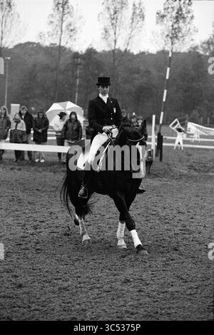 Dressage, Marienweide, 02-10-1993 Whizgle News, Dutch Desk, pays-Bas, 1950-2000 Un cavalier en tenue formelle guide élégamment un cheval noir dans une arène, en faisant preuve de précision et d'équilibre. Les spectateurs en arrière-plan regardent attentivement, entourés d'arbres et de tentes. Banque D'Images