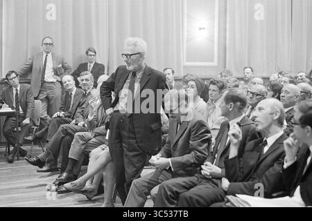 Centre-ville Teach-In, réunions, 24-10-1969 Whizgle News, Dutch Desk, pays-Bas, 1950-2000 Un groupe d'hommes et de femmes s'assoient dans un cadre formel, écoutant attentivement comme un individu se tient au centre, engageant le public avec un comportement confiant. L'atmosphère suggère une discussion ou un débat sérieux, avec diverses expressions reflétant l'intérêt et la contemplation parmi les participants. Banque D'Images