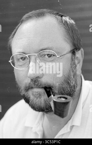 Henk van Dorp, Pipe Smoking World Championships, 16-08-1993 Whizgle News, Dutch Desk, pays-Bas, 1950-2000 Un homme d'âge mûr avec une barbe et des lunettes regarde soigneusement, tenant une pipe dans la bouche. Son expression suggère la contemplation, peut-être la réflexion sur des expériences ou des idées passées. Il porte une simple chemise blanche, ajoutant à l'ambiance simple mais introspective. Banque D'Images
