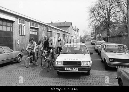 Le comité du Conseil passe par Haarlem, cyclisme, pistes cyclables, cyclistes, Haarlem, pays-Bas, 28-03-1981 Whizgle News, Dutch Desk, pays-Bas, 1950-2000 Un groupe de personnes à vélo se dirige vers une voiture de police garée dans une rue étroite bordée de véhicules anciens et de bâtiments industriels en arrière-plan. Banque D'Images