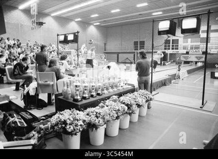 Finales de bowling Beyneshal, Bowling, Haarlem, pays-Bas, 21-06-1987 Whizgle News, Dutch Desk, pays-Bas, 1950-2000 un événement intérieur animé mettant en vedette une foule réunie dans des gradins, avec des participants engagés dans une compétition de bowling. Au premier plan, un ensemble de trophées ornés de fleurs évoque l'importance de la journée, tandis qu'un tableau de bord et des écrans de télévision capturent l'action sur les voies. Banque D'Images
