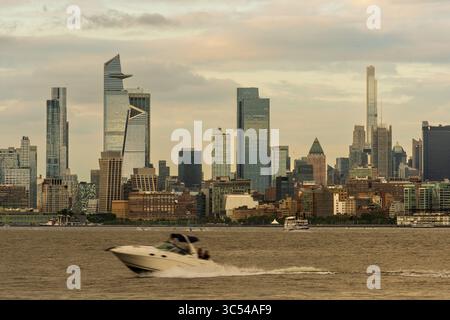 Jersey City, NJ - US - 19 juillet 2025 Un hors-bord traverse le fleuve Hudson alors que les tours élégantes et modernes de Hudson Yards et Midtown Manhattan s'élèvent Banque D'Images