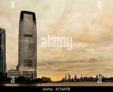 Jersey City, NJ - US - Jul 19, 2025 Goldman Sachs Tower s'élève au-dessus de Jersey City au crépuscule, sa façade en verre élégante brille contre les nuages dramatiques, avec M Banque D'Images